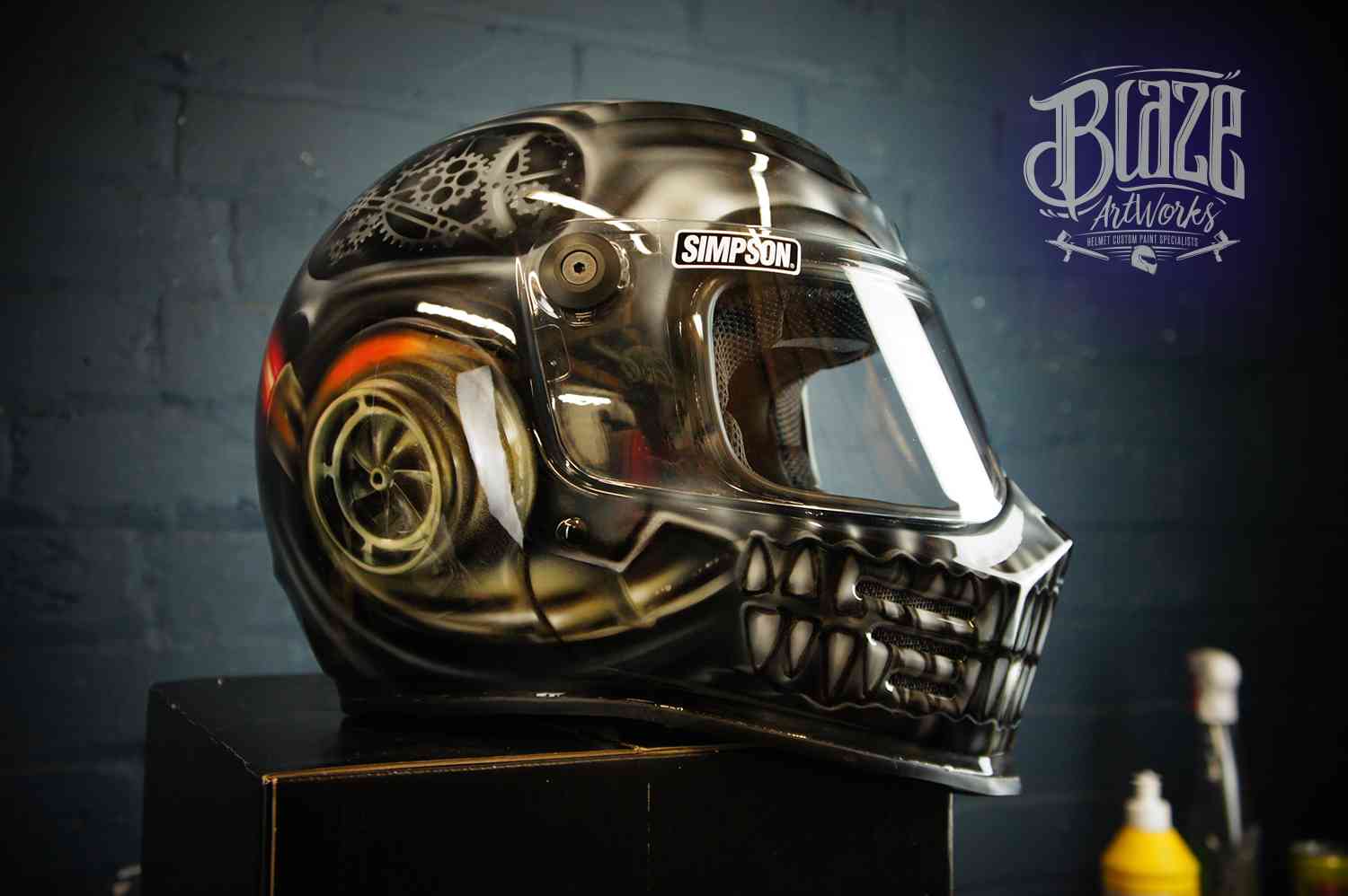 Black motorcycle helmet with detailed skull and snake airbrush design featuring golden accents and realistic death imagery